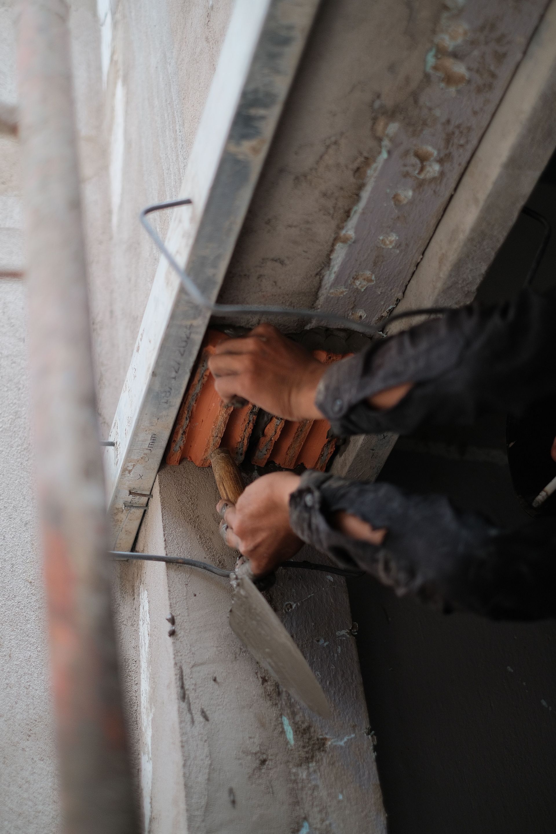 Worker repairing structure with trowel, showcasing detailed craftsmanship.